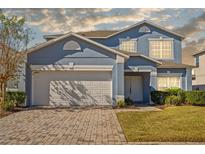 Two-story house with a gray exterior, white garage door, and a landscaped lawn at 755 Kildrummy Dr, Davenport, FL 33896