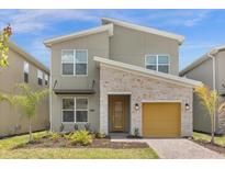 Two-story home with a modern design, stone accents, and a yellow garage door at 8940 Play Through Dr, Davenport, FL 33896