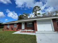 Brick house with a white garage door and landscaping at 2355 Cypress Rd, Deland, FL 32724