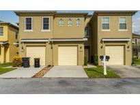 Tan two-story townhome with attached garage and mailbox at 476 Lake Shore Pkwy, Davenport, FL 33896