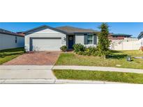 Single-story house with brick driveway, landscaped yard, and attached garage at 1251 Citrus Landing Blvd, Davenport, FL 33837