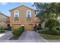 Tan two-story townhome with two-car garage and landscaped front yard at 5159 Sabal Branch Cv, Oviedo, FL 32765