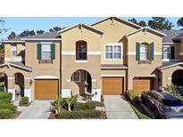 Tan three-story townhome with two-car garage and landscaping at 446 Penny Royal Pl, Oviedo, FL 32765