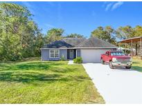 Newly built home with a gray exterior, white garage door, and a spacious yard at 40501 W 5Th Ave, Umatilla, FL 32784