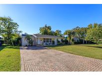 Brick paved driveway leading to a charming ranch home with a well-manicured lawn at 4272 Kendrick Rd, Orlando, FL 32804