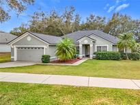 Single-story house with gray exterior, two-car garage, and well-manicured lawn at 11114 Oakshore Ln, Clermont, FL 34711