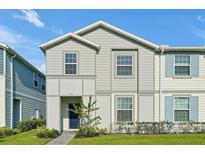Two-story house with gray siding, blue door, and landscaping at 866 Paradise Dr, Davenport, FL 33897