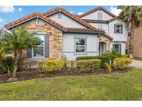 Two-story home with stone accents and a tile roof, showcasing a landscaped front yard at 12023 Gold Creek Trl, Windermere, FL 34786