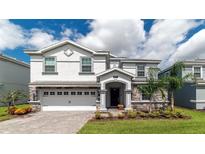 Two-story house with gray and white exterior, stone accents, and a three-car garage at 8823 Interlocking Ct, Davenport, FL 33896