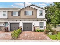 Two-story townhome with two-car garage, brick pavers, and landscaping at 4701 New Orleans Cv, Oviedo, FL 32765