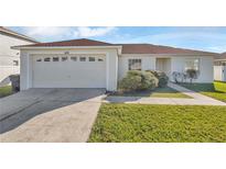 Single-story house with a two-car garage and a well-maintained lawn at 610 Crane Dr, Poinciana, FL 34759