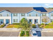 Front view of a light blue townhome with solar panels and a small tree in front at 8921 Sydney Ave, Kissimmee, FL 34747