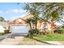 Inviting home with a two-car garage, landscaped yard, and palm trees at 167 Castaway Beach Way, Kissimmee, FL 34746