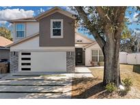 Two-story house with modern gray and white exterior, stone accents, and a spacious driveway at 2561 Montego Bay Blvd, Kissimmee, FL 34746