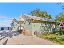 Green house exterior with a metal roof, wooden steps, and a spacious yard at 3420 Lake Harney Cir, Geneva, FL 32732