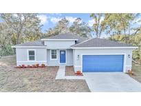 New single-story home with gray exterior, blue garage door, and landscaping at 14390 Sw 44Th Ave, Ocala, FL 34473