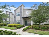 Modern two-story townhome with stone accents and landscaped front yard at 830 Pebble Beach Dr, Davenport, FL 33896