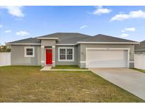 One-story home with gray exterior, red door, and two-car garage at 1917 Michigan Drive, Poinciana, FL 34759