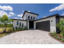Modern two-story home with a gray paver driveway and attached garage at 326 Spinnaker Ct, Auburndale, FL 33823