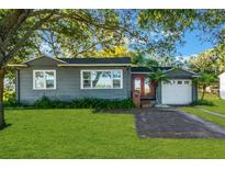 Gray house with a white garage, red door and nicely landscaped lawn at 20 Maynard Ave, Orlando, FL 32803