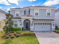 Two-story house with gray siding, a three-car garage, and well-manicured landscaping at 1670 Moon Valley Dr, Davenport, FL 33896
