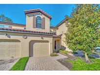 Tan two-story townhome with two-car garage and landscaping at 8169 Roseville Rd, Davenport, FL 33896