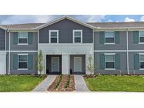 Two-story townhome with gray siding, teal shutters, and a landscaped front yard at 4322 Lana Ave, Davenport, FL 33897