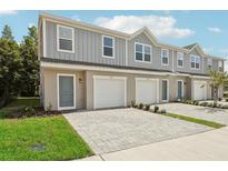Three-unit townhome building with gray siding, attached garages, and paved driveways at 1215 Fan Palm Dr, Davenport, FL 33897