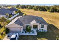 One-story house with gray roof, landscaping, and a driveway at 1218 Coda Ct, Dundee, FL 33838
