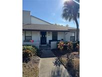 Bright white exterior of a condo with a walkway and tropical landscaping at 2810 Plaza Terrace Dr # 2810, Orlando, FL 32803