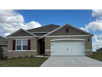 One-story home with a two-car garage, and a brown and white exterior at 2952 Waterlily Way, Poinciana, FL 34759