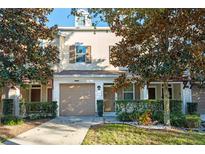Tan two-story townhome with attached garage and landscaping at 659 Fortanini Cir, Ocoee, FL 34761