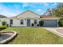 One-story house with a gray door, attached garage, and well-manicured lawn at 1812 Hudson Ct, Kissimmee, FL 34759