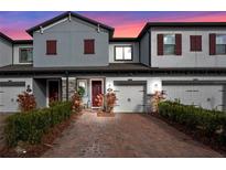 Two-story townhome with gray siding, red shutters, and a brick driveway at 308 Rustic Loop, Sanford, FL 32771