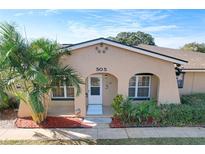 Tan house with a white door, palm trees, and red mulch at 505 Polaris Loop # 107, Casselberry, FL 32707