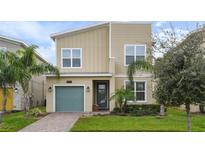 Two-story home with teal garage door, landscaped yard, and palm trees at 8942 Cabot Cliffs Dr, Davenport, FL 33896