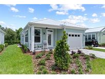 Charming craftsman style home with rocking chairs on the front porch and landscaped yard at 12078 Lakeshore Way, Oxford, FL 34484