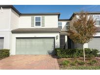 Two-story townhome with gray garage door, landscaping, and brick pavers at 947 Robin Holly St, Ocoee, FL 34761