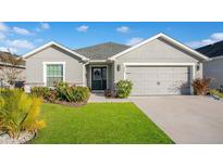 Single-story home with gray exterior, two-car garage, and landscaped lawn at 933 Aruba Ave, Mulberry, FL 33860