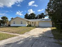 House exterior featuring a single-story home with a two-car garage and a well-maintained lawn at 4617 Frisco Cir, Orlando, FL 32808