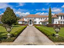 Grand two-story home with tile roof, stone accents, and manicured landscaping at 9343 Tibet Pointe Cir, Windermere, FL 34786