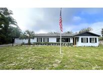 Newly renovated home with white exterior, landscaping, and American flag at 1625 Normandy Way, Leesburg, FL 34748