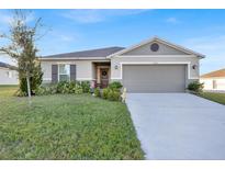 One-story house with gray siding, two-car garage, and landscaped front yard at 2325 Crossandra St, Mascotte, FL 34753