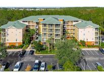 Exterior elevation of a multi-story condominium building with balconies, surrounded by parking and landscaping at 9051 Treasure Trove Ln # 102, Kissimmee, FL 34747