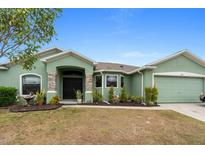 Green one-story home with a two-car garage and landscaped front yard at 5761 Woodruff Way, Lakeland, FL 33812