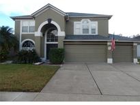 Two-story home with a two-car garage, landscaped yard, and an American flag at 915 Ekana Green Ct, Oviedo, FL 32765