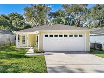 Charming yellow house with a white garage door and a well-maintained lawn at 2436 Princeton Ave, Sanford, FL 32771