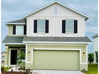 Two-story home with a green and beige exterior, black shutters, and attached garage at 3007 Tackle Dr, Leesburg, FL 34748