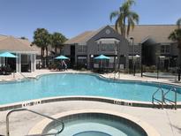 Inviting community pool with a separate hot tub, shaded seating areas, and lush landscaping at 3100 Parkway Blvd # 110, Kissimmee, FL 34747