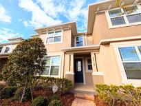 Tan three-story townhome with a blue door and landscaping at 8419 Lovett Ave, Orlando, FL 32832